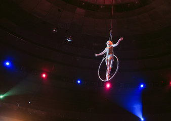 Aerial acrobat in the ring. A young girl performs the acrobatic elements in the air ring.