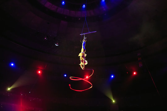 Aerial acrobat in the ring. A young girl performs the acrobatic elements with tape in the air ring.