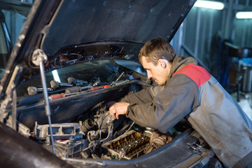 Auto mechanic working in garage. Repair service.