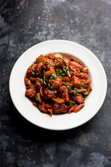 Indian Chilli Chicken dry, served in a plate over moody background. Selective focus