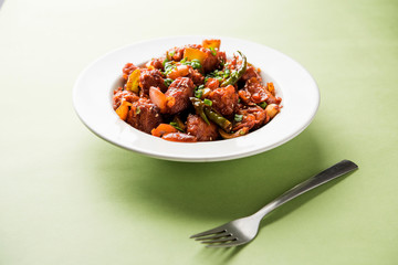 Indian Chilli Chicken dry, served in a plate over moody background. Selective focus