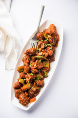 Indian Chilli Chicken dry, served in a plate over moody background. Selective focus
