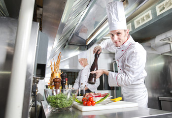 The chef prepares a dish in the kitchen of restoran.