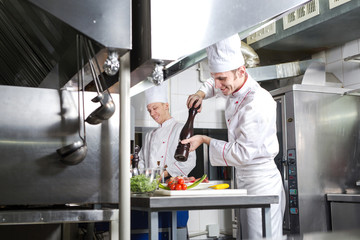 The chef prepares a dish in the kitchen of restoran.