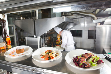 the distribution table in the kitchen of the restaurant. the chef prepares a meal on the background of the finished dishes.