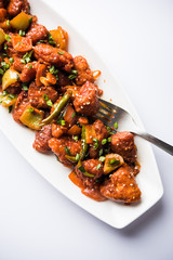 Indian Chilli Chicken dry, served in a plate over moody background. Selective focus