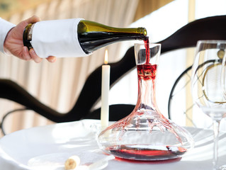 A sommelier pouring red wine into decanter