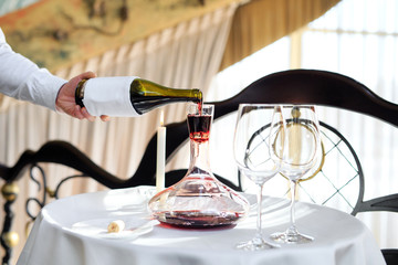 A sommelier pouring red wine into decanter