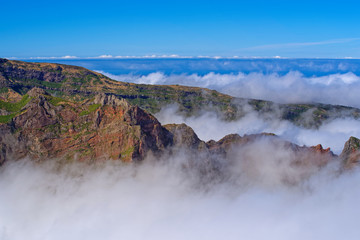 Mountain peaks in the clouds against clear blue sky. Portuguese island of Madeira