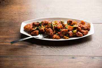 Indian Chilli Chicken dry, served in a plate over moody background. Selective focus