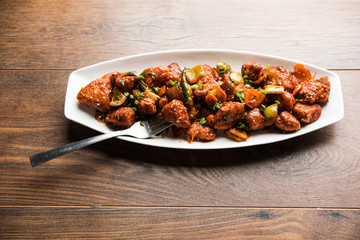 Indian Chilli Chicken dry, served in a plate over moody background. Selective focus