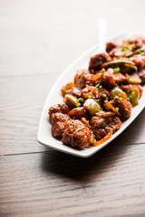 Indian Chilli Chicken dry, served in a plate over moody background. Selective focus
