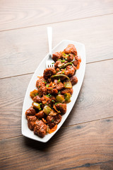 Indian Chilli Chicken dry, served in a plate over moody background. Selective focus
