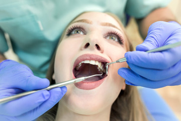 Close-up picture of young woman sitting in the dentist's chair with opened mouth at dentist's office while having examination.