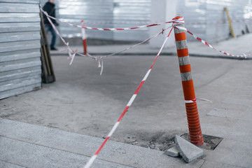 Orange fence cone with striped tape at building