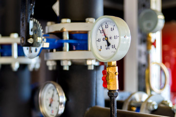 Closeup of manometer, measuring gas pressure. Pipes and valves at industrial plant. Pressure gauge, measuring instrument close up on hot water, oil or gas pipeline