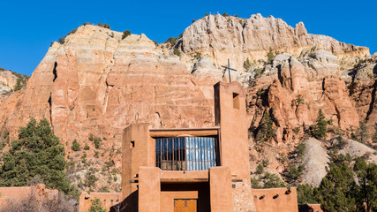 Widescreen view of high colorful cliffs and rock formations and the Abbey Church at the Monastery of Christ in the Desert near Abiquiu, New Mexico
