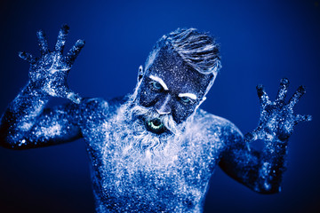 Concept. Portrait of a bearded man. The man is painted in ultraviolet powder.
