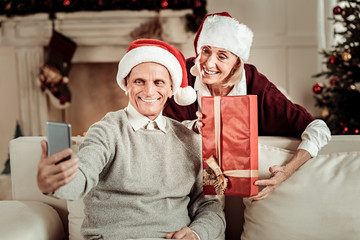 Aged pleasant couple having fun and making photo.