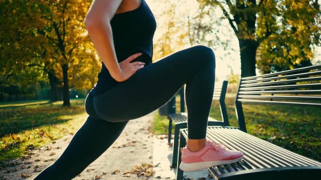 Sport Woman running walking in the fall forest on sunny autumn day, close-up legs sport shoes
