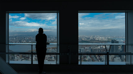 Fototapeta na wymiar Silhouette of a man overlooking Osaka city.