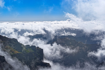 Dense clouds over mountains range on sunny day on Portuguese island of Madeira