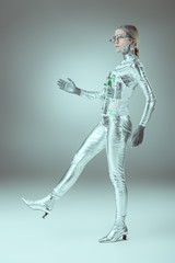 Fototapeta na wymiar side view of silver woman robot walking on grey, future technology concept
