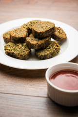 Cilantro cake or Kothimbir Vadi is a popular maharashtrian cuisine made with cilantro leaves. served with tomato ketchup. selective focus