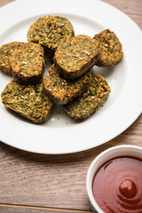 Cilantro cake or Kothimbir Vadi is a popular maharashtrian cuisine made with cilantro leaves. served with tomato ketchup. selective focus