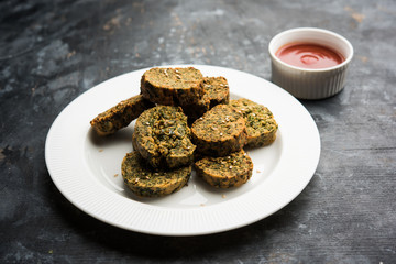 Cilantro cake or Kothimbir Vadi is a popular maharashtrian cuisine made with cilantro leaves. served with tomato ketchup. selective focus