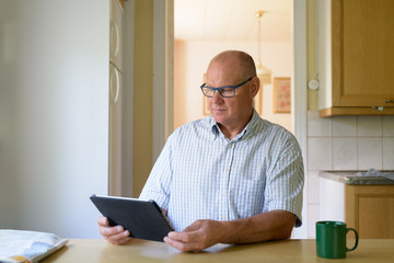 Senior Man Using Digital Tablet Near The Window