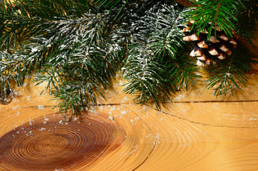 snow-covered Christmas tree branch with pine cone on wood background. Xmas background