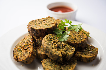Cilantro cake or Kothimbir Vadi is a popular maharashtrian cuisine made with cilantro leaves. served with tomato ketchup. selective focus