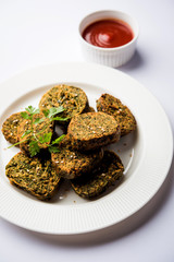 Cilantro cake or Kothimbir Vadi is a popular maharashtrian cuisine made with cilantro leaves. served with tomato ketchup. selective focus