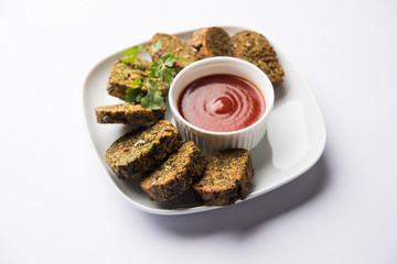 Cilantro cake or Kothimbir Vadi is a popular maharashtrian cuisine made with cilantro leaves. served with tomato ketchup. selective focus