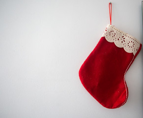 A red and white christmas sock is hanging on a white wall.