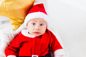close-up of a baby boy in a Santa Claus suit lying on the blanke