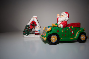 A Christmas gingerbread house stands next to a Santa Claus in a green car.