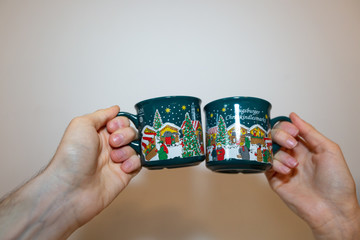 Two people clinking glasses with some traditional winter and christmas cups.