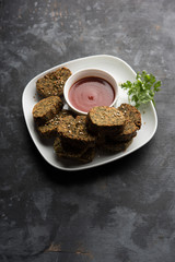 Cilantro cake or Kothimbir Vadi is a popular maharashtrian cuisine made with cilantro leaves. served with tomato ketchup. selective focus