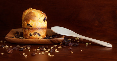 PLUM CAKE CON PASAS Y CUCHARA DE MADERA SOBRE FONDO OSCURO