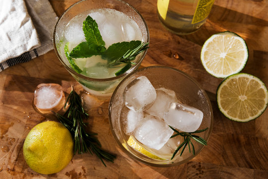 Glass of Gin Tonic with lime, mint, rosemary and ice and lemon, rosemary and ice