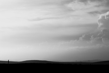 Depressive black and white landscape on the plain with the silhouette of a man. Background about...