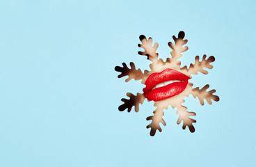 Fototapeta na wymiar Beautiful Plump Bright Lips Of a Young Beautiful Woman with Red Lipstick Look Into the Pattern of Snowflakes made of Colored Paper. Snowflake. Christmas Patterns. Blue Paper