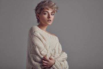 Portrait of young girl with blond hair wear sweater looking at camera isolated on gray background