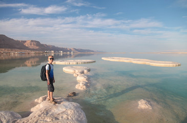 Blond boy enjoying bright day on Dead sea beautiful salt shore. Israel.