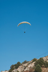 Fototapeta na wymiar Paraglider is flying in the blue sky. Paragliding in the sky on a sunny day.