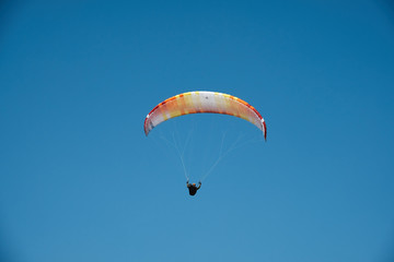 Paraglider is flying in the blue sky. Paragliding in the sky on a sunny day.