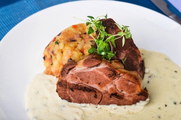 Baked pork,mashed potato, green thyme and pepper sauce, closeup.