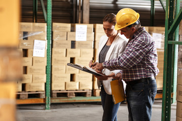 Female manager and warehouse worker checking list and inventory on the shelf in storehouse.